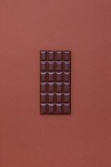 Dark chocolate tablet on brown background
