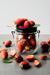 Fresh strawberry lies in a glass jar on a white background. Ripe berry