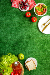 Flat lay of picnic setting with basket and summer food on red cloth