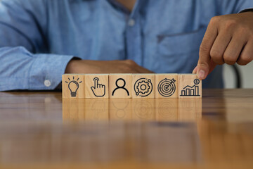 Businessman hand arranging wood block with icon business strategy and Action plan.