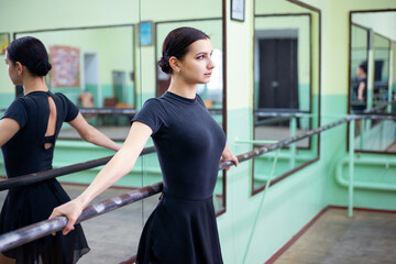 Beautiful girl dancer standing near barre, concentrated look. Ballerina in the dance hall on her...