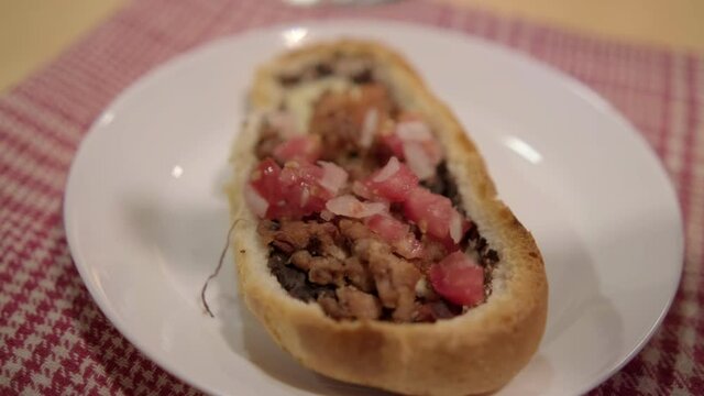 Traditional Mexican mollete on a plate above white and red checkered napkin