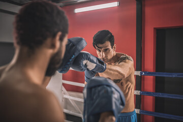 Young men fighting on a boxing ring and looking determined