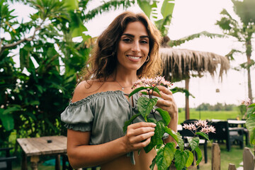 Cheerful lady enjoying scent of exotic flowers during summer holiday