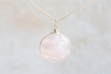 Mineral rose quartz stone sterling silver simple pendant on neutral background