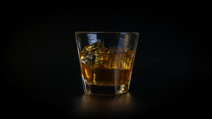 Whiskey drink or cocktail, honey brown, in a glass, full of cold, sparkling ice cubes.