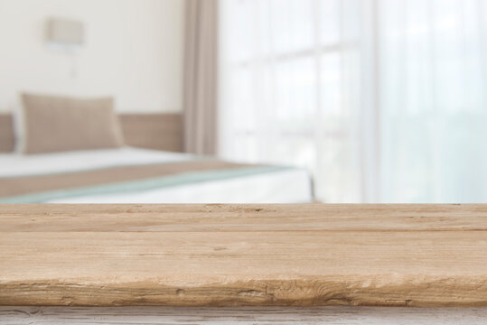 Wooden table top in front of defocused bedroom interior background