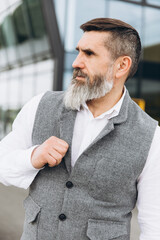 Naklejka premium Portrait of a gray bearded and brutal man spending time on the clean urban spaces.