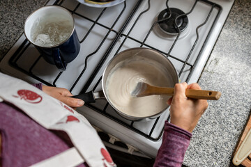 Top view of woman cooking bechamel sauce at home