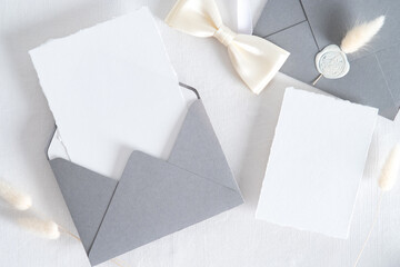 Flatlay wedding stationery set on white background. Open envelope with invitation card mockup,...