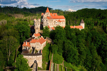 Ancient royal Moravian castle Pernstejn, standing on a hill covered green forest against partly...