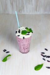 Milkshake with honeysuckle  berries, cream, mint leaves in glass with straw on white background