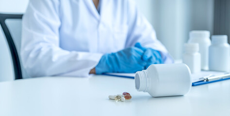 Medicine pill and bottle in front of doctor or pharmacist with a prescription at the pharmacy office, healthcare and medical check-up concept