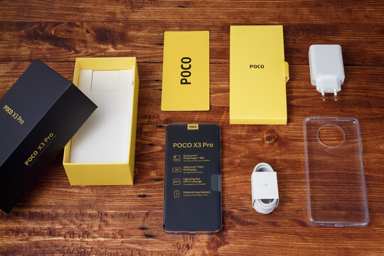 New smartphone Poco X3 Pro with packaging, power supply, USB cable and case on a wooden table. Moscow, Russia, April 29, 2021.