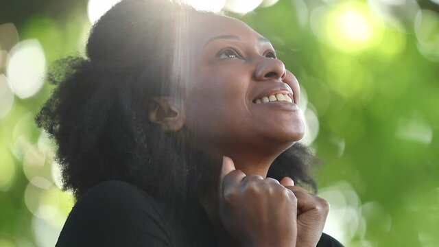 Happy woman looking at sky with HOPE and FAITH, spiritual African person outside sunlight lens-flare
