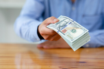 Business man hands counting US Dollar bills or paying in cash .