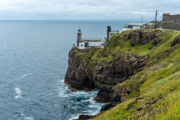 Fototapeta na wymiar Santa Catalina de Lekeitio lighthouse and its beautiful cliffs on a cloudy spring morning, with the sea in the background, landscapes of Bizkaia. Basque Country