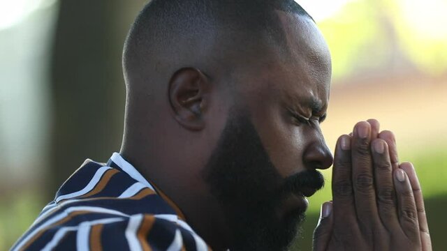 African man eyes closed praying to God for help and support