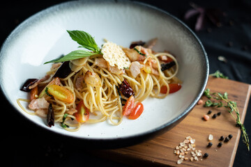 Spaghetti dry chili, olive oil, sweet basil with bacon. served on black ceramic dish on wooden board
