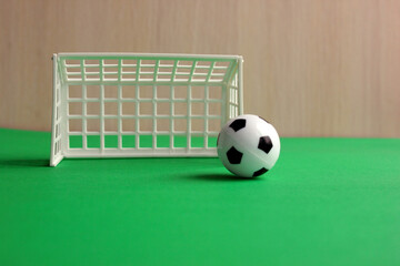 Football. A football in a small gate on a gray background. Mini football. Sports game. The ball is near the gate. Copy the space. Healthy, active outdoor play.