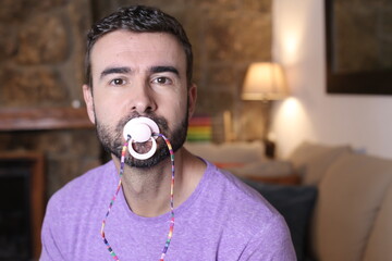 Spoiled grown up man licking a pacifier to control a tantrum