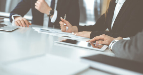 Unknown businessmen and woman sitting, working and discussing questions at meeting in modern office, close-up