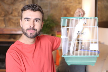 Man holding exotic white bird in a cage  - Powered by Adobe