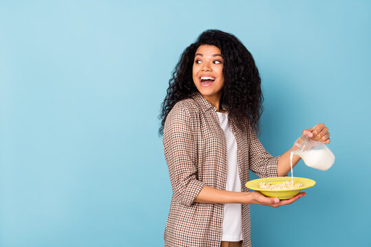 Photo Of Pretty Impressed Dark Skin Woman Dressed Shirt Cooking Milk Cereal Looking Back Empty Space Isolated Blue Color Background