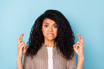 Photo of upset curly hairdo young lady crossed fingers bite lip wear brown shirt isolated on vivid...