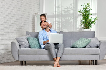 happy little girl hugsher father while he working from home