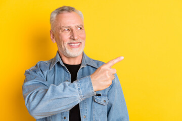 Photo of funky senior granddad point look empty space wear jeans jacket isolated on vivid yellow...