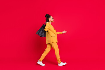 Profile full length photo of nice lady go shake hand with bags wear yellow blazer isolated on vivid red color background