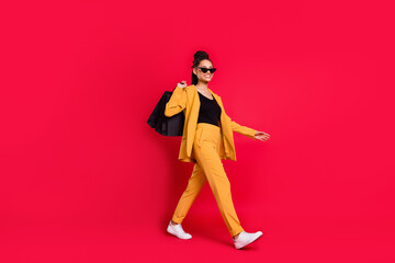 Profile full size photo of cool lady go with bags wear yellow blazer isolated on vivid red color background