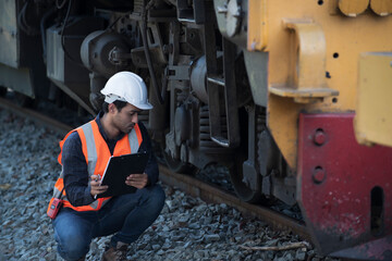 Railroad worker checking up wheels and braking system of freight train. Safety inspector or maintenance engineer checking rail tracks at station.