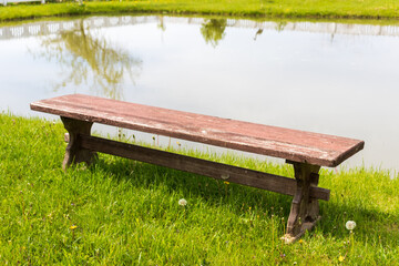 Fototapeta premium Red bench with a tree by the shore of a lake in spring