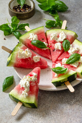 Healthy seasonal dieting and nutrition, summer snack. Watermelon pizza with feta cheese and basil on a gray stone tabletop. Copy space.