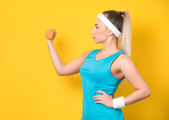 Side view of fitness young woman training gym with dumbbell, isolated on yellow background. Half length of fit sportswoman lifting weights. Fitness motivation. 80s styling