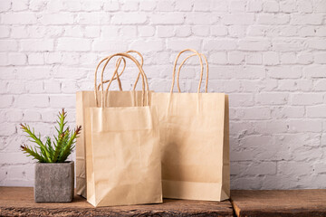 Group of kraft paper bags wit copy space on wood table with white white brick wall background.
