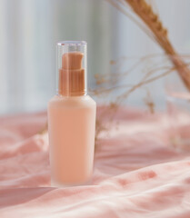 cosmetic bottle cream lotion on pink fabric background