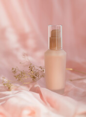 Obraz na płótnie Canvas cosmetic bottle cream lotion on pink fabric background