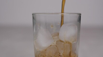 Slow motion 4K. A sweet  cold soft drink is poured into a glass filled with ice cubes. refreshing delicious drink Thirst quenching drink.