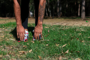 Fototapeta na wymiar A man athlete doing workout on the forest, training, fitness workout flexibility. Active lifestyle youth, close-up hand sneakers
