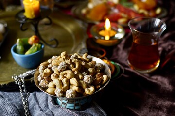Nuts mix on a black table background with candles and turk lale with tea