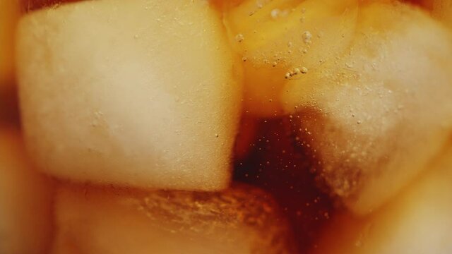 Slow motion 4K. A sweet  cold soft drink is poured into a glass filled with ice cubes. refreshing delicious drink Thirst quenching drink.