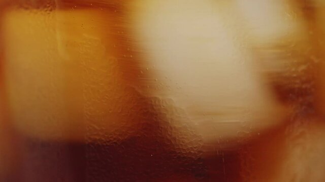 Slow motion 4K. A sweet  cold soft drink is poured into a glass filled with ice cubes. refreshing delicious drink Thirst quenching drink.
