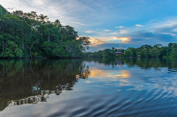 Amazon river rainforest sunset reflection. Amazon jungle is located in Brazil, Bolivia, Colombia, Ecuador, French Guyana, Peru, Suriname, Venezuela.