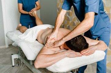 Four-handed back and shoulder massage for men in a beauty salon. Health Care Concept