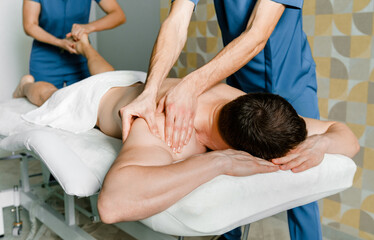 Fototapeta na wymiar Four-handed back and shoulder massage for men in a beauty salon. Health Care Concept