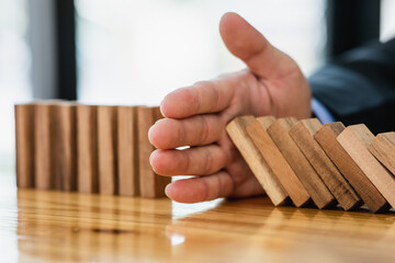 Businessman protect wooden block fall to planning and strategy in risk to business Alternative and prevent. Investment Insurance ,Business risk control concept,