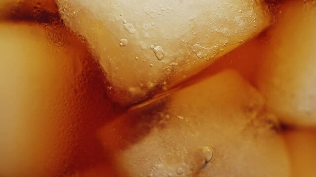 Slow motion 4K. A sweet  cold soft drink is poured into a glass filled with ice cubes. refreshing delicious drink Thirst quenching drink.